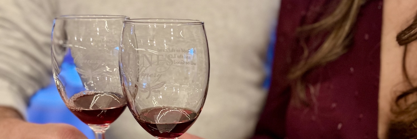 Two people with two wine glasses at a wood topped bar