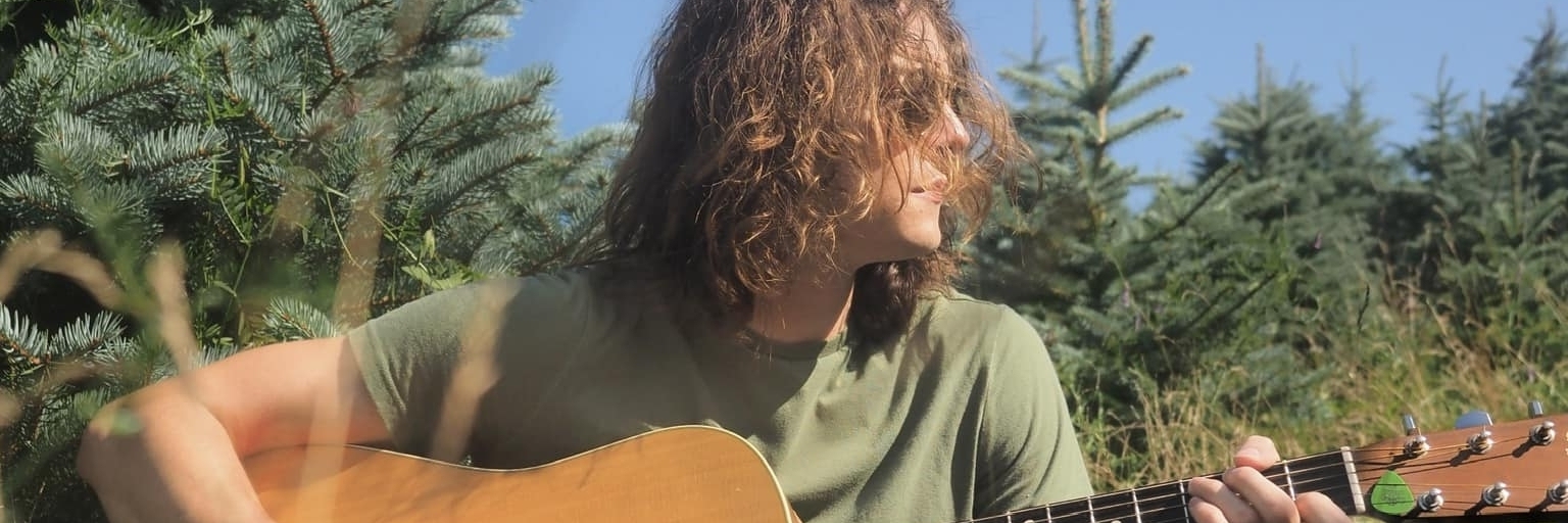 Riley Johnson on guitar in a field