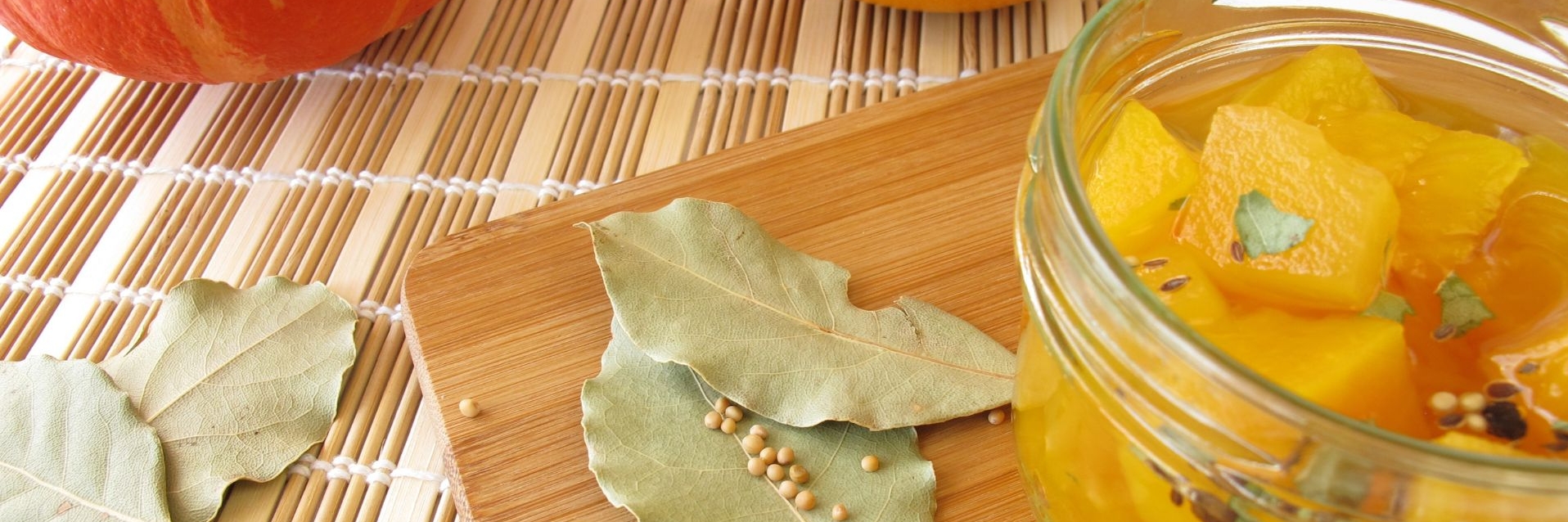 a canning jar of Sweet Pickled Squash garnished with bay leaves