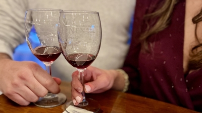 Two people with two wine glasses at a wood topped bar