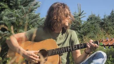 Riley Johnson on guitar in a field