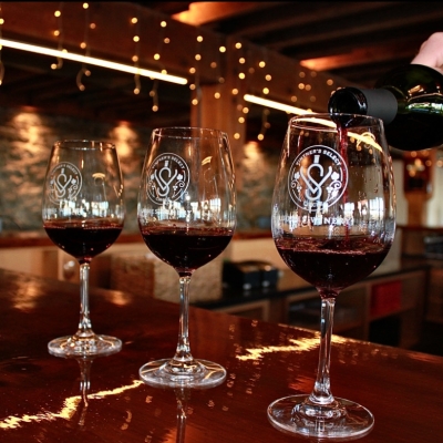 Pouring tastes of red wine into glasses.